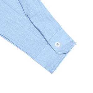 Détail du poignet d'une chemise en lin bleu clair avec texture et bouton blanc