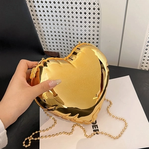Close-up of heart-shaped gold metallic mini bag with reflective finish and beaded chain