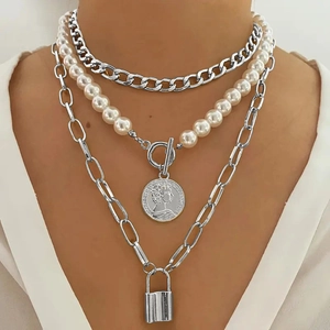Close-up of layered baroque pearl necklace with silver coin and padlock charms on a model