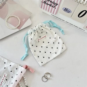 Polka dot canvas drawstring pouch detail featuring jewelry storage with soft pastel accents