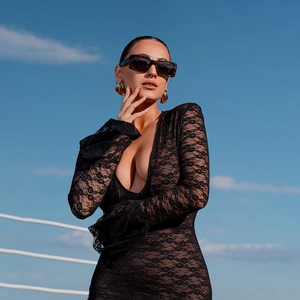 Détail du décolleté plongeant en V et des manches longues en dentelle sur la robe noire