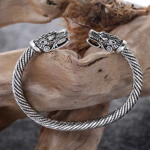 Close-up of vintage silver wolf head terminals on a twisted viking style open bangle