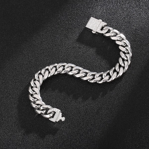 Macro shot of a silver Cuban link bracelet with diamond-encrusted clasp on black texture