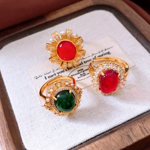 Close-up of vintage 24k gold-plated rings with oval ruby and emerald gemstones and pearls