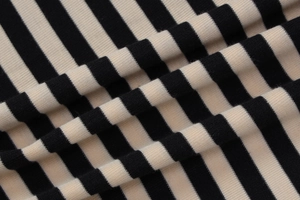 Détail macro du tissu en maille rayée noir et beige avec une texture douce de qualité