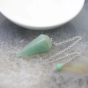 Macro di un pendolo in avventurina verde con catena d'argento su pietra naturale grezza