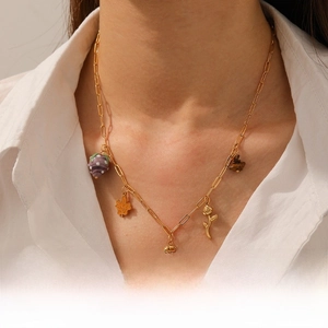 Detailed view of a gold paperclip chain necklace with assorted tropical and bohemian charms