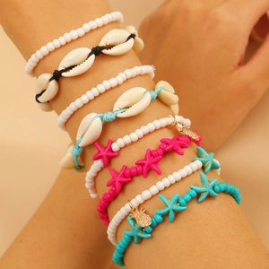 Set di braccialetti boho con perline, stelle marine e conchiglie indossati per l'estate