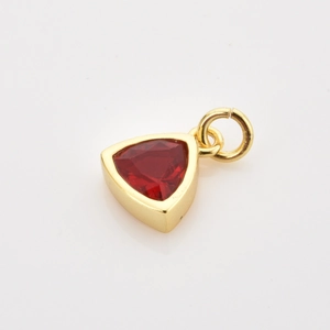 Close-up of a gold-plated triangle charm with a bright red zircon and a jump ring connector