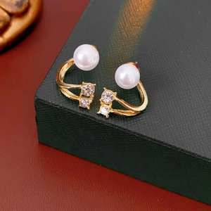 Elegant gold pearl stud earrings with zircon drops on textured emerald jewelry box