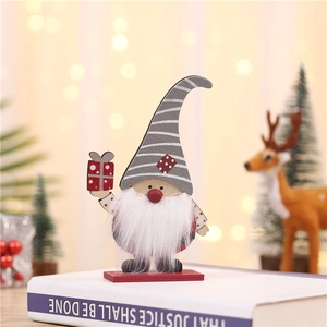 Gnome de Noël en bois avec chapeau rayé gris et boîte cadeau sur une table de fête décorée