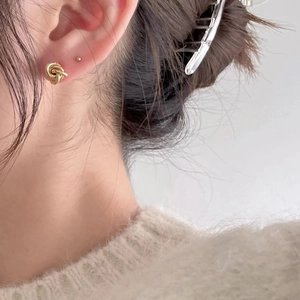 Primo piano di orecchini a nodo dorato indossati da una modella per un look minimalista