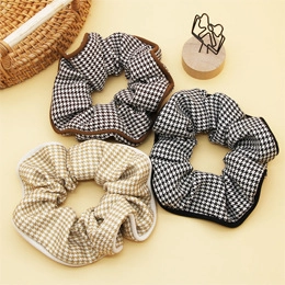 Dettaglio di scrunchies con motivo pied de poule nero, marrone e beige con bordi a contrasto