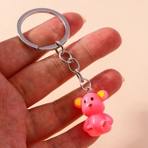Detailed view of pink resin bear charm keychain with metal ring and chain held in hand