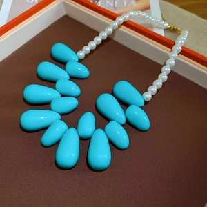 Détail de pendentifs turquoise en forme de goutte et de perles blanches sur le collier