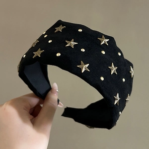 Detail of a black suede headband featuring gold star and dot metal rivet embellishments