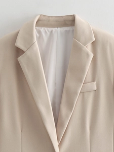 Detail view of beige blazer lapel and button showing premium suit fabric texture
