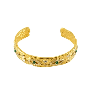 Vintage gold textured cuff bracelet featuring green stone and crystals on white background