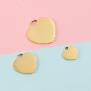 Three gold heart pendants in different sizes on a soft pink and blue background