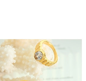 Close-up of golden textured ring with a clear round gemstone on a soft background
