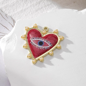 Detailed view of heart-shaped evil eye pendant with red marble texture and pearls