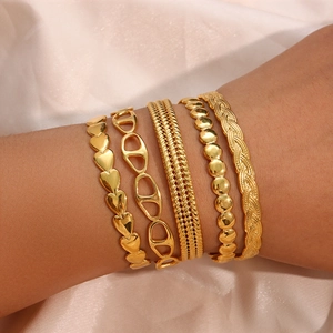 Detail of 5-piece gold twisted braid bracelets on soft pink satin fabric background