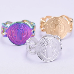 Detailed view of St. Benedict medal rings with Cuban link bands in gold and silver