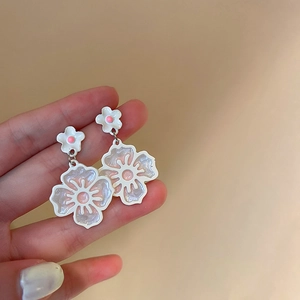 Gros plan détaillé de boucles d'oreilles tulipes blanches avec finition nacrée et accents roses