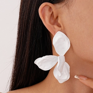 Macro side view of a model wearing large white matte flower petal statement earrings