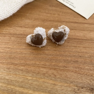 Macro shot of heart-shaped tweed earrings in brown and beige tones on wooden surface