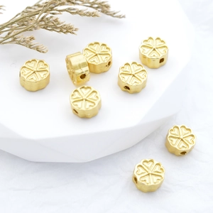 Golden flower and clover DIY jewelry beads with embossed texture on white stands