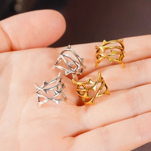 Dettaglio di quattro anelli e clip punk a spina in oro e argento tenuti in mano