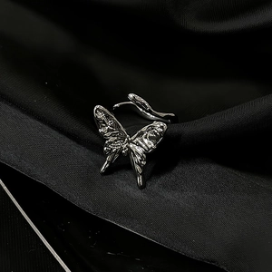 Macro shot of a silver butterfly ring with polished finish on black silk fabric