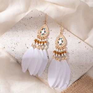 Detailed view of bohemian earrings with white feathers and blue beads on linen