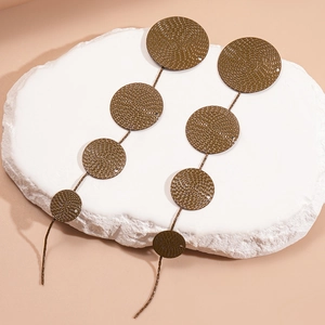 Detail of vintage bronze round textured fringe earrings on decorative stone pedestal