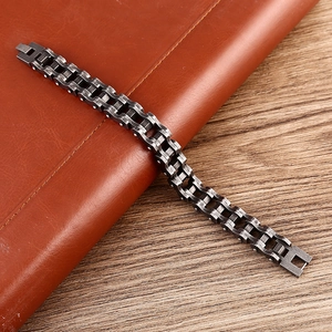 Industrial gunmetal stainless steel bicycle chain bracelet on leather and wood background