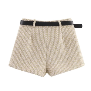 Detail of light beige tweed shorts with gold weave texture and a thin black waist belt