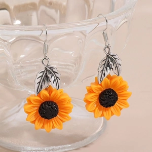 Macro shot of yellow lemon flower earrings with silver leaves hanging on glassware
