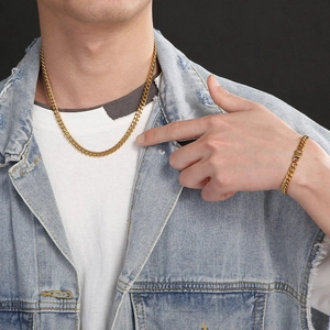 Close-up of a gold-plated Cuban chain necklace and bracelet set worn by a male model