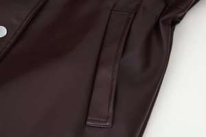 Detailed macro view of dark brown leather jacket featuring side pockets and silver snap button