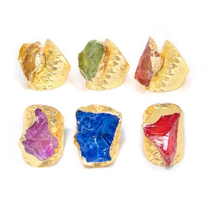 Vista plana de cristales naturales coloridos montados en anillos martillados dorados
