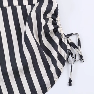 Detail of black and white vertical striped shirt featuring adjustable side drawstring