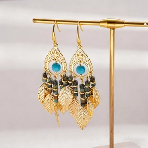 Détail de boucles d'oreilles vintage dorées avec perles turquoise et feuilles