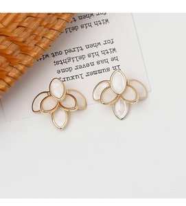 Detail view of French vintage white enamel flower earrings with golden petal outlines