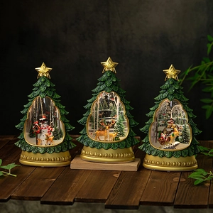 Three Christmas tree music boxes with Santa and snowman scenes on a wooden table