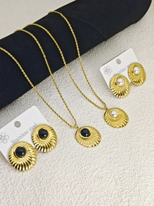 Detail view of stainless steel shell pendant necklaces and earrings with pearls and gems
