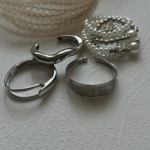 Detail view of multi-layer silver metal bangles and white pearl beaded bracelet set