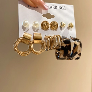 Close-up of six-pair earring set featuring pearls, gold hearts, and leopard print hoops