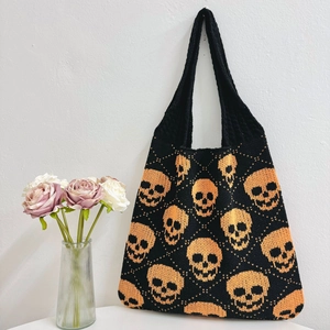 Handmade knitted tote bag with orange skull patterns on black background for Halloween