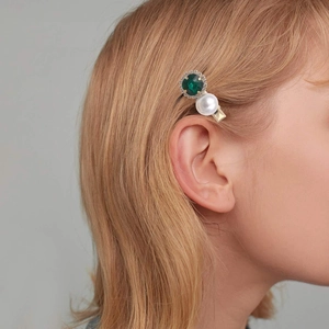 Detailed view of hair clip with green gemstone, white pearl and small rhinestones